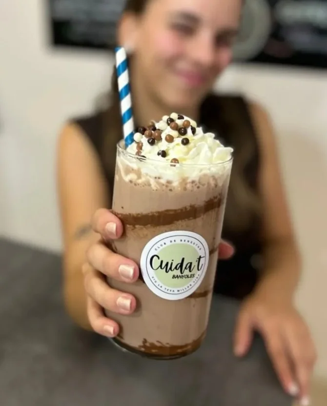 Una dona oferint el seu batut de xocolata de Cuida't Banyoles a càmera
